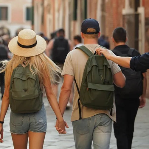 Sac à dos antivol – Vue arrière d’un couple marchant dans une ruelle touristique, tandis qu’un pickpocket tente d’accéder discrètement au sac du jeune homme.