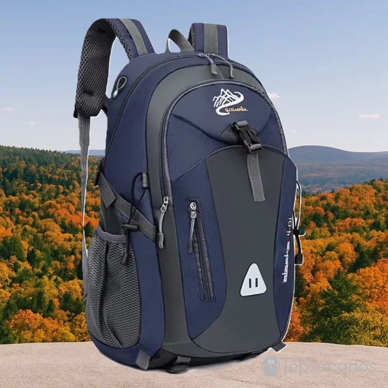 Sac à dos 40L randonnée bleu foncé posé sur une pierre avec forêt automnale en arrière-plan