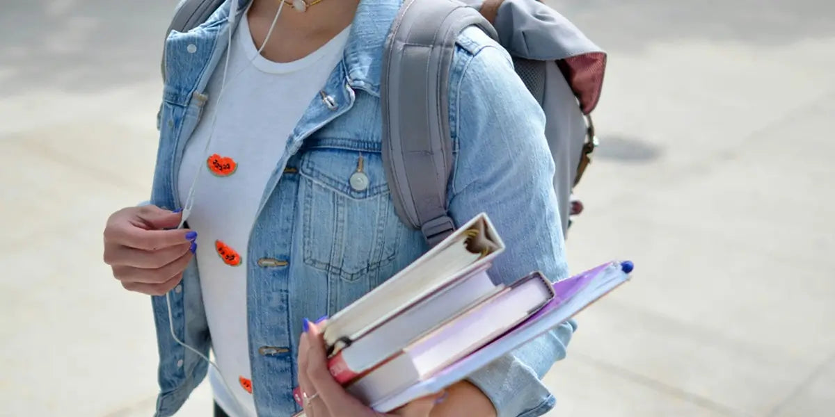 Élève portant un sac à dos d'école gris et transportant des livres – Idéal pour la rentrée scolaire