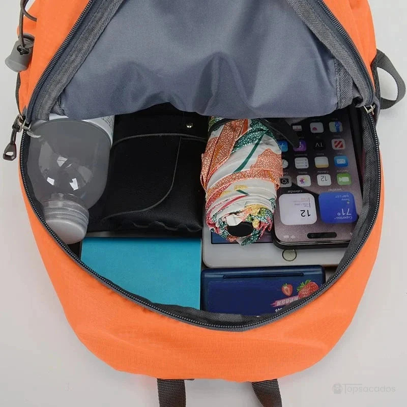 Petit Sac à dos randonnée femme avec compartiment principal bien organisé contenant gourde, portefeuille, parapluie et smartphone.