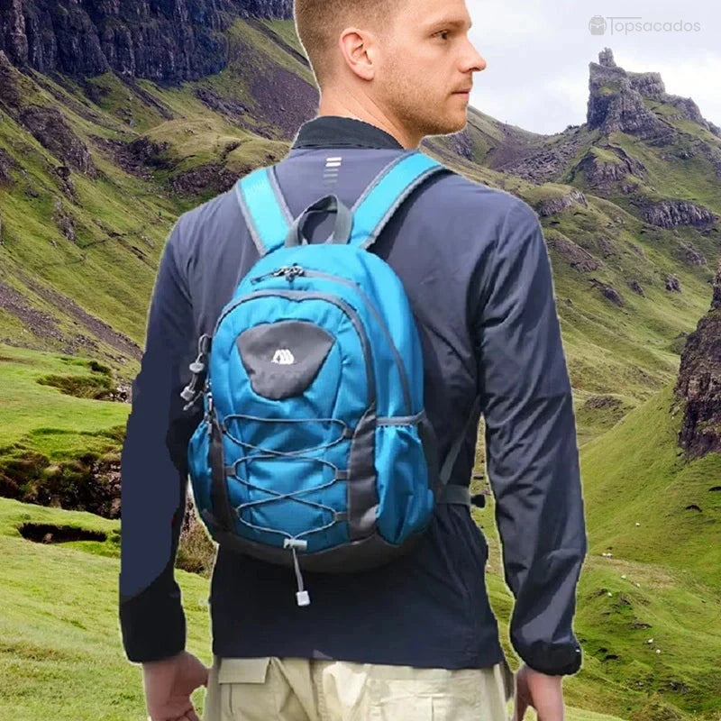 Petit Sac à dos randonnée porté par un homme dans un paysage montagneux verdoyant, prêt pour l'aventure.
