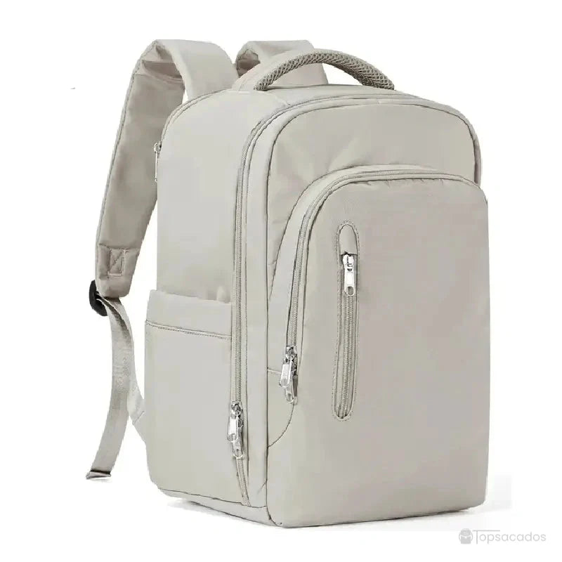 Sac à dos 40x20x25 gris clair avec grande poche frontale et bretelles épaisses, posé en studio sur fond uni blanc.