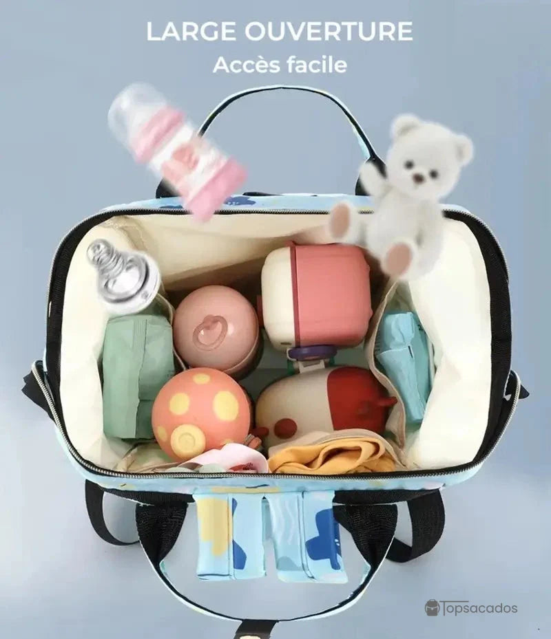 Sac à dos à langer avec large ouverture zippée, vue du dessus montrant les rangements internes avec biberons, couches et jouets, sur fond bleu clair.