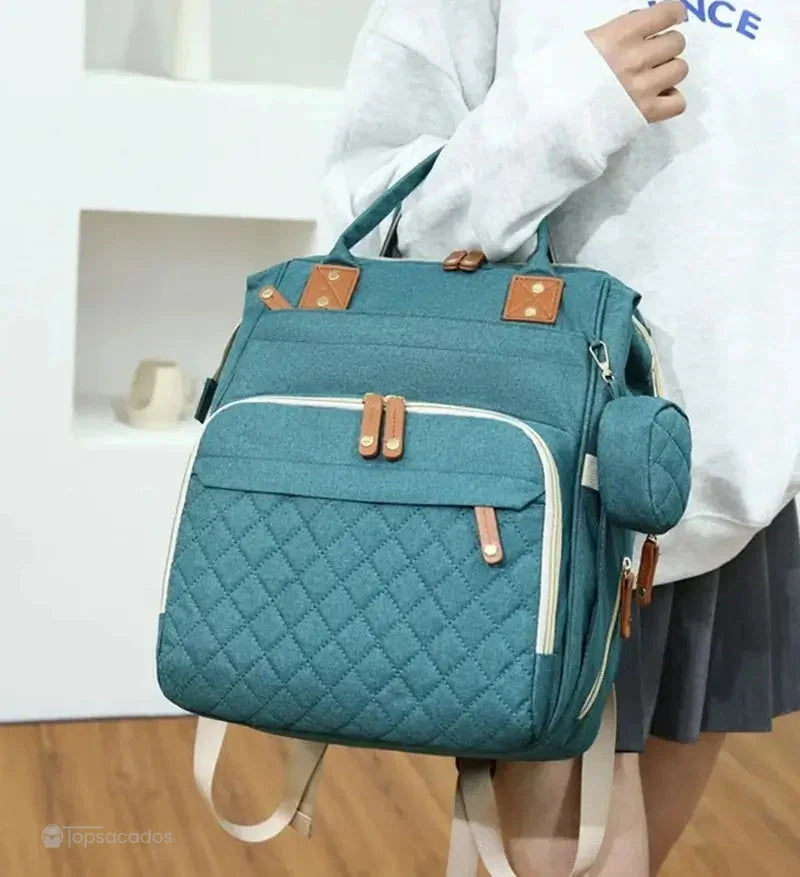 Sac à dos à langer avec port usb illustrant deux poches frontales utilisées pour une tablette et un smartphone, sur fond beige avec pictogrammes numériques.