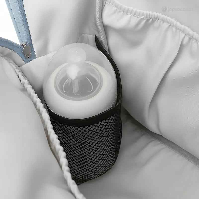 Sac à dos à langer élégant avec biberon rangé dans une poche filet intérieure, gros plan