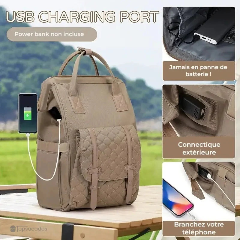 Sac à dos à langer multifonctions avec port USB intégré, présenté sur une table extérieure, permettant de recharger un téléphone en déplacement.