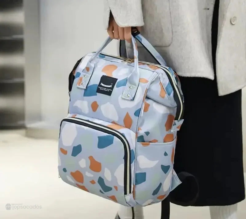 Sac à dos à langer à imprimé terrazzo porté à la main dans un environnement intérieur moderne, mettant en valeur son design élégant et pratique.