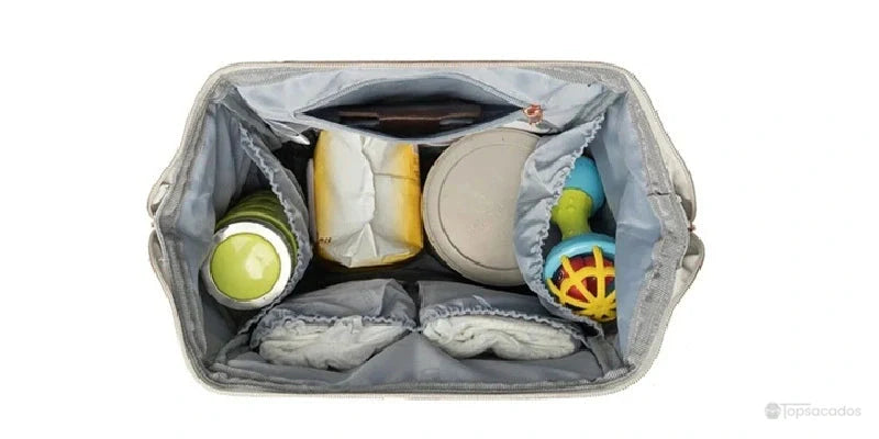 Sac à dos à langer Urbain et chic vu de dessus, avec compartiments organisés pour couches, biberons, jouets et lingettes.