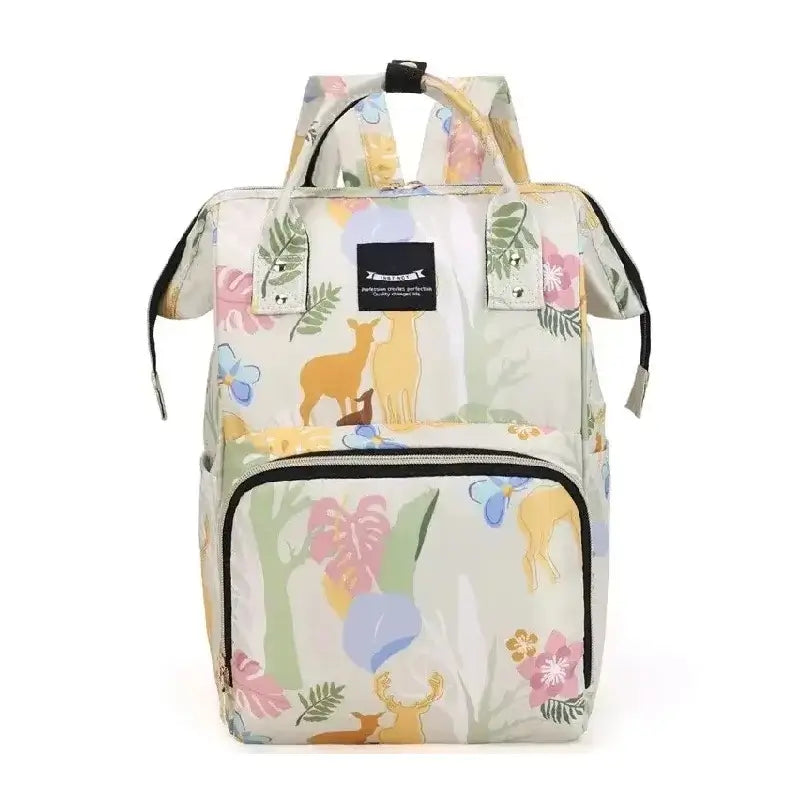 Sac à dos à langer beige jaune à motif animalier discret représentant des cerfs et des feuillages tropicaux, avec poche avant noire et poignées supérieures solides, mis en scène sur fond neutre.