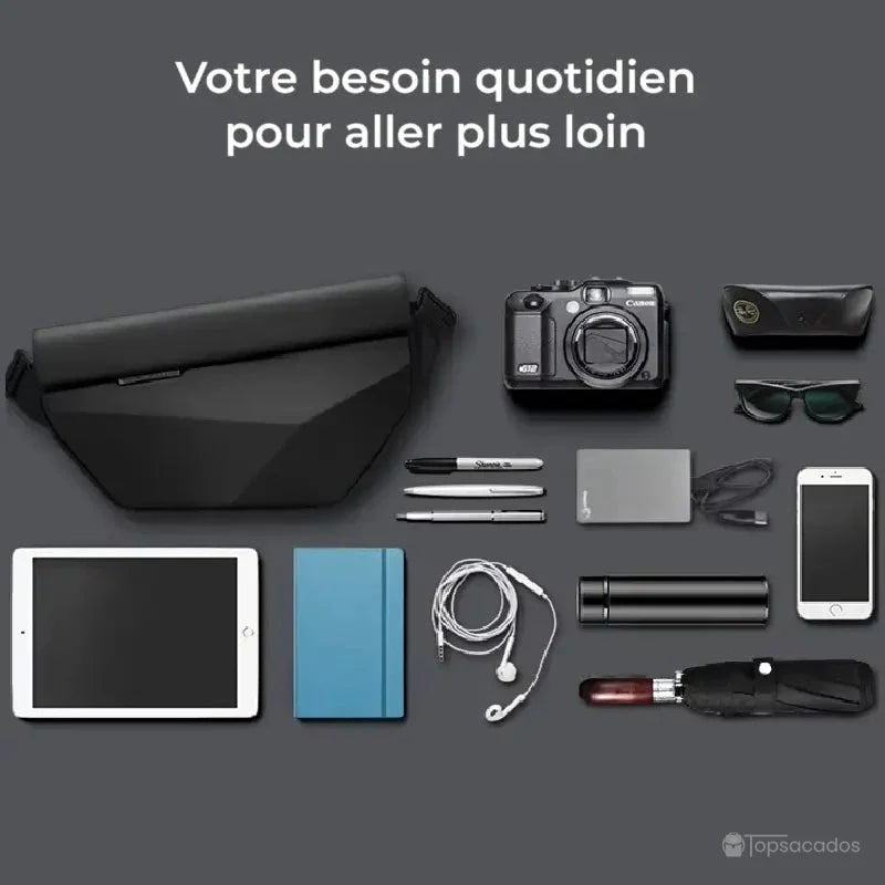 Sac à dos bandoulière noir avec objets du quotidien exposés sur fond gris : tablette, appareil photo, carnet, lunettes et câbles.
