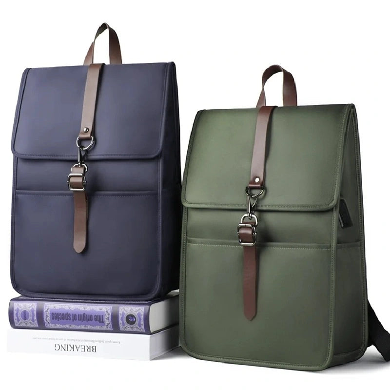 Sac à dos collège antivol fille bleu et vert posés sur des livres, avec design rectangulaire élégant et boucle métallique décorative, sur fond blanc.