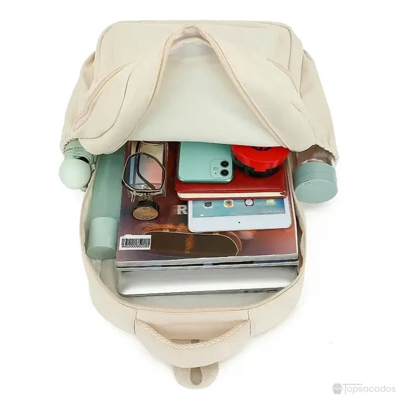 Sac à dos collège ouvert et rempli de livres, tablette, lunettes, gourde et objets du quotidien d’un élève.