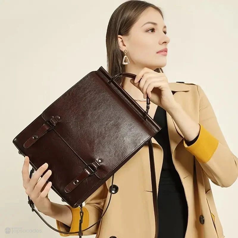 Sac à dos cuir Femme avec rabat marron porté à la main par une femme en trench beige, sur fond uni