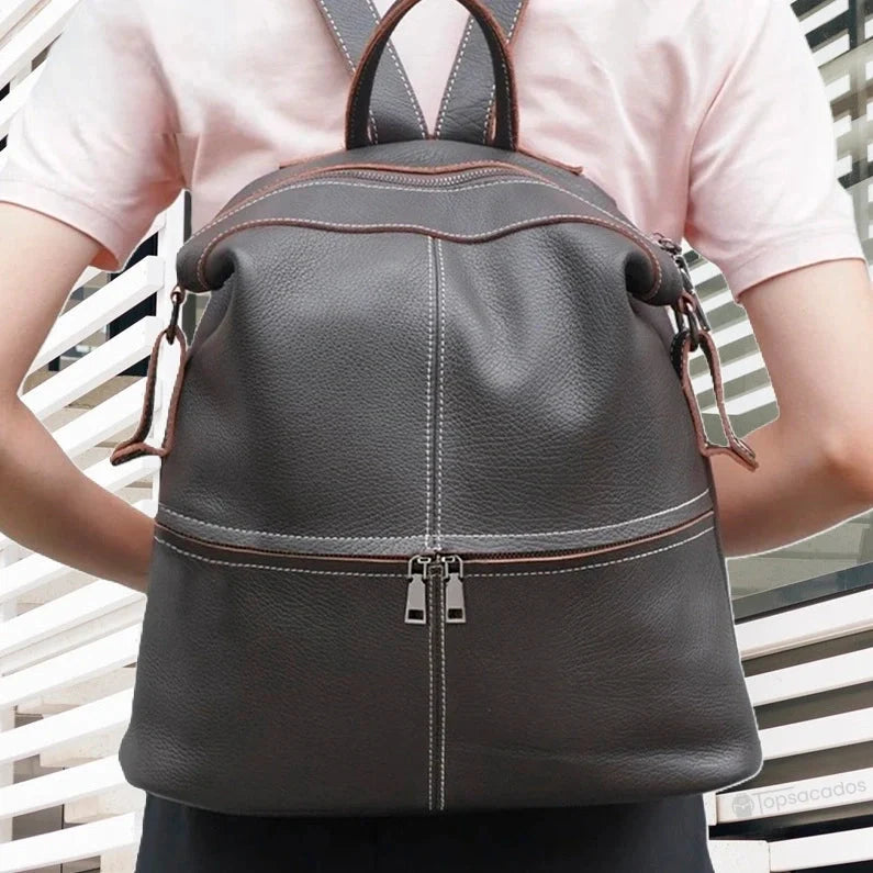 Sac à dos cuir femme porté sur le dos d'une femme en extérieur devant un mur moderne