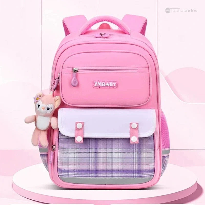 Sac à dos fille ce1 rose posé sur un présentoir rose dans un décor pastel, vu de face