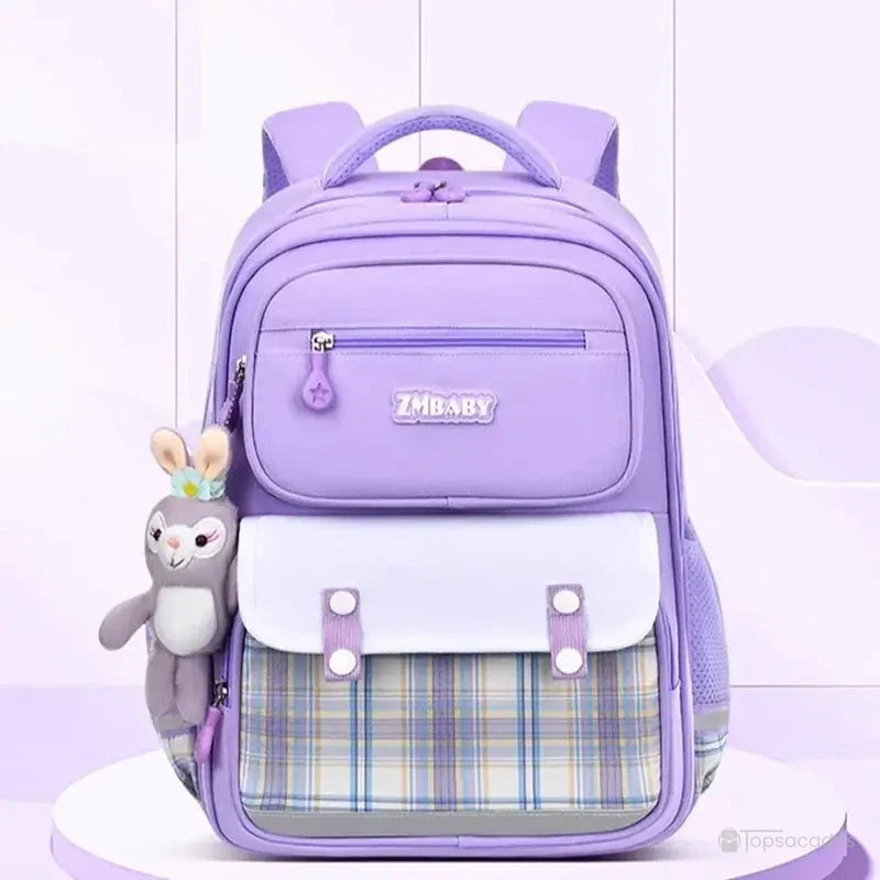 Sac à dos fille ce1 violet mis en scène dans un décor pastel, posé sur un socle lumineux