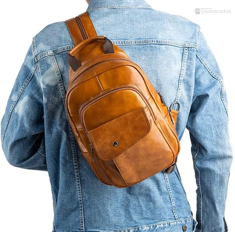 Sac à dos homme cuir de vachette porté en travers dans le dos par-dessus une veste en jean, style casual et dynamique, sur fond blanc.