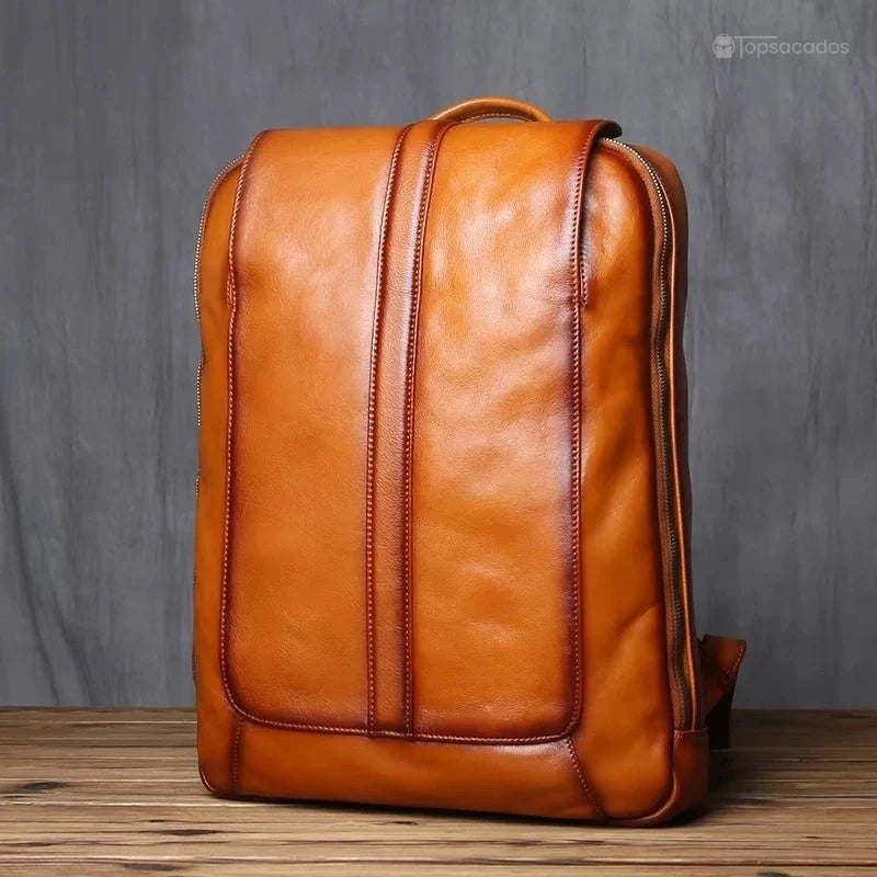 Sac à dos homme cuir marron vu de face, design élégant avec lignes verticales de couture en cuir, posé sur sol en bois.