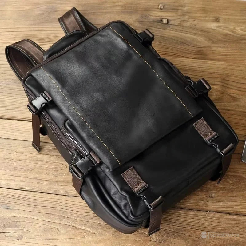 Sac à dos homme cuir noir vu de dessus, posé à plat sur du bois brut, mettant en avant sa forme et ses fermetures.