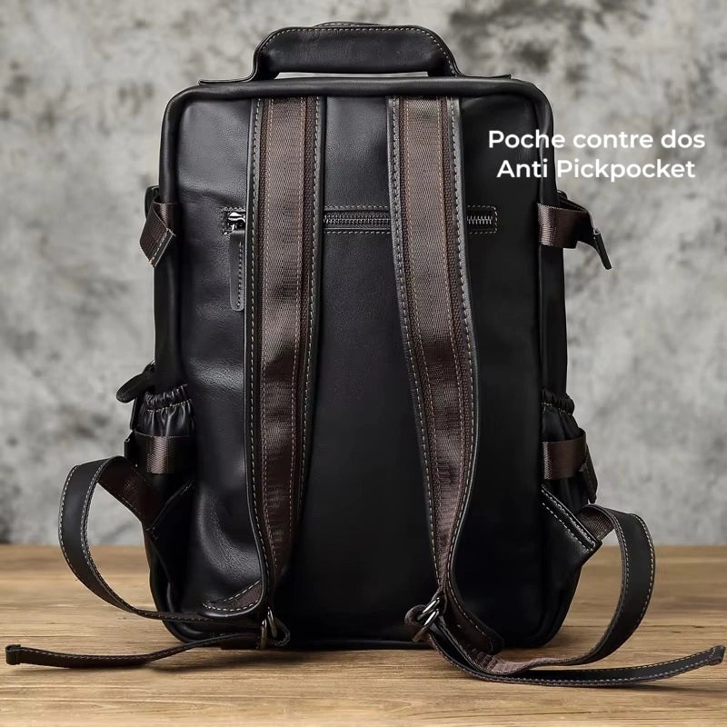 Sac à dos homme cuir noir vue arrière avec bretelles renforcées et poche antivol discrète contre le dos, sur fond béton.