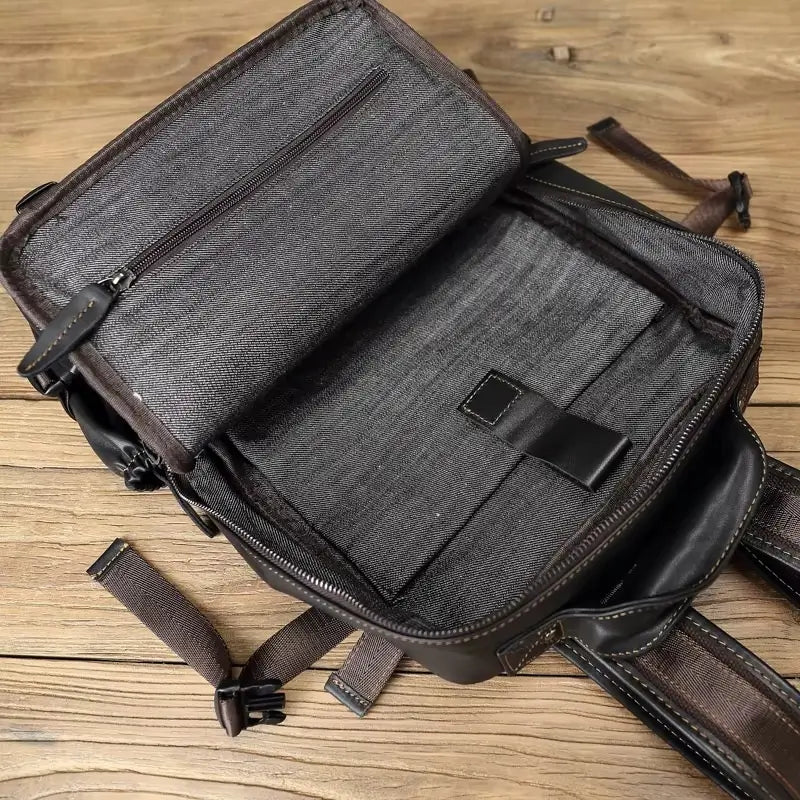 Sac à dos homme cuir noir intérieur spacieux vide avec poche zippée, photographié sur fond de planches en bois clair.