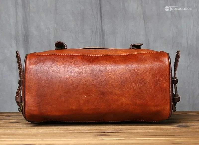 Sac à dos homme cuir vintage vu de dessous, posé sur une surface en bois, montrant un cuir lisse et patiné de qualité.