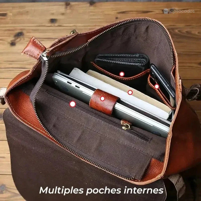 Sac à dos homme cuir vintage ouvert vu de dessus, révélant plusieurs compartiments internes avec tablette, carnet et portefeuille en intérieur marron.