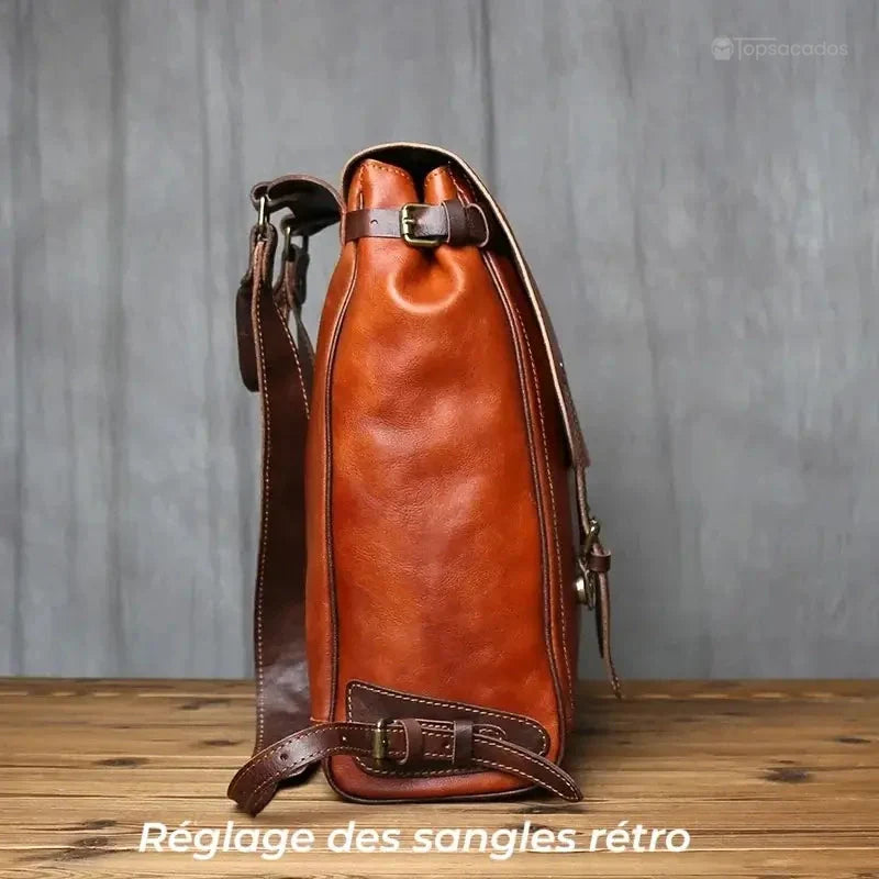 Sac à dos homme cuir vintage vu de profil, avec sangles ajustables et silhouette élancée posée sur un plancher en bois.