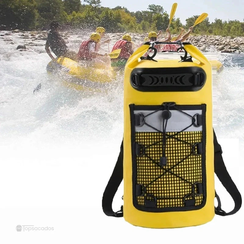 Sac à dos imperméable jaune en premier plan, utilisé lors d’une descente en rafting, avec pagaie en fond et éclaboussures d’eau.