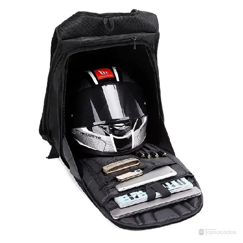 Sac à dos moto en fibre de carbone ouvert, contenant un casque de moto, une tablette et plusieurs objets rangés dans des poches internes organisées.