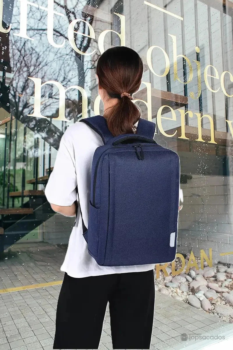 Sac à dos ordinateur Femme porté par une femme de dos, en extérieur devant une vitrine, ambiance citadine moderne.