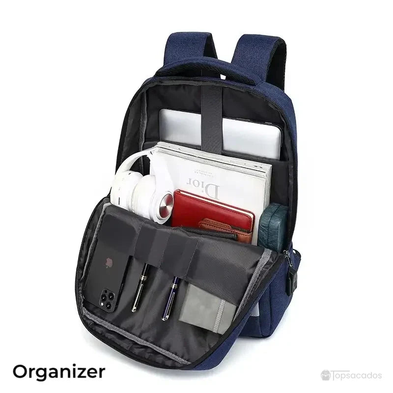 Sac à dos ordinateur Homme ouvert, compartiment principal rempli avec ordinateur, magazine, portefeuille, écouteurs et stylos.