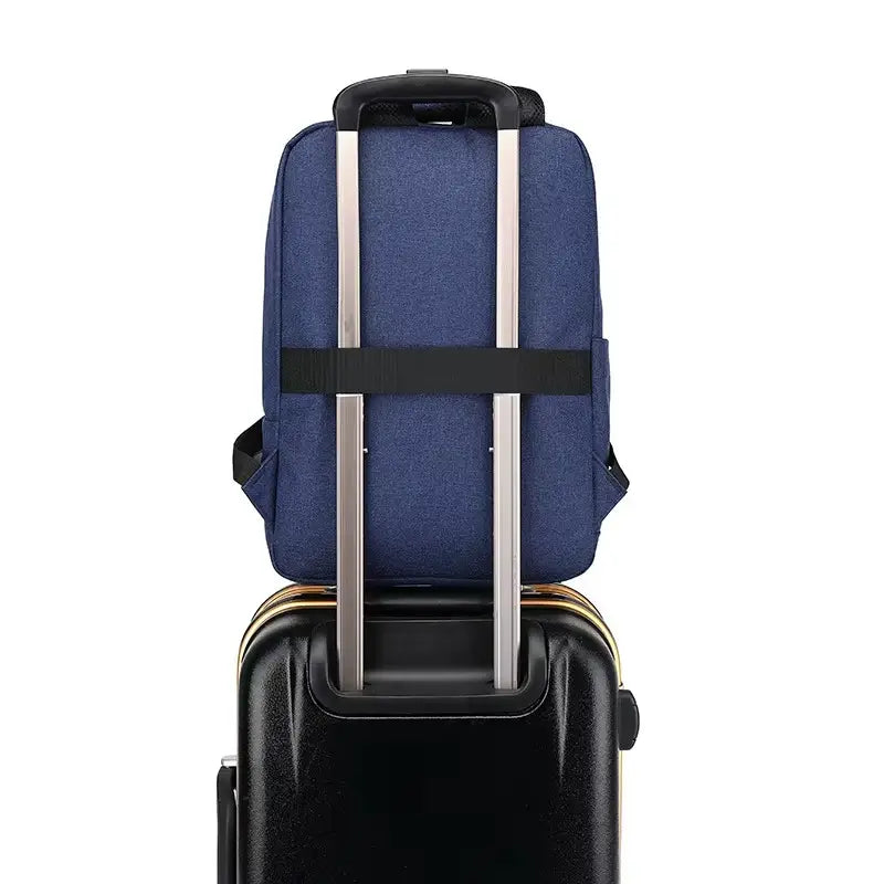 Sac à dos ordinateur Homme fixé à la poignée télescopique d’une valise noire, grâce à une bande de maintien.