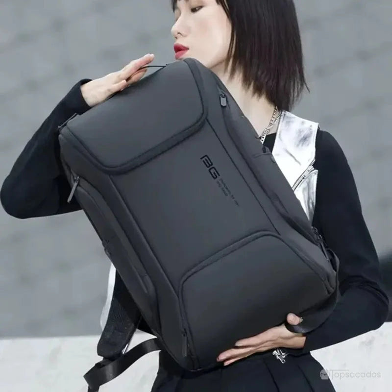 Sac a dos ordinateur portable multipoches porté à la main par une femme moderne en tenue noire, mettant en avant la sobriété et l’élégance du sac dans un environnement urbain.