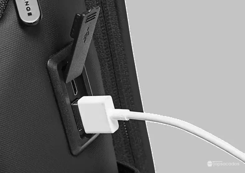 Sac a dos ordinateur portable multipoches avec port USB externe intégré sur le côté, vu de près avec câble blanc branché, idéal pour charger un appareil en déplacement.
