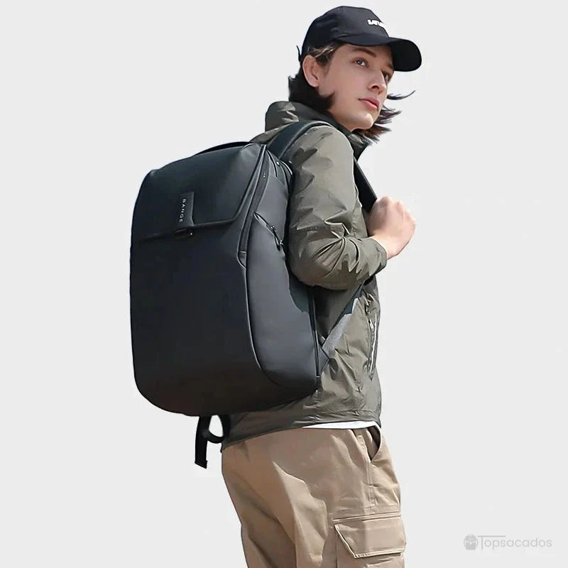 Sac à dos ordinateur portable ouverture par le dessus porté par un homme en extérieur, habillé de façon décontractée