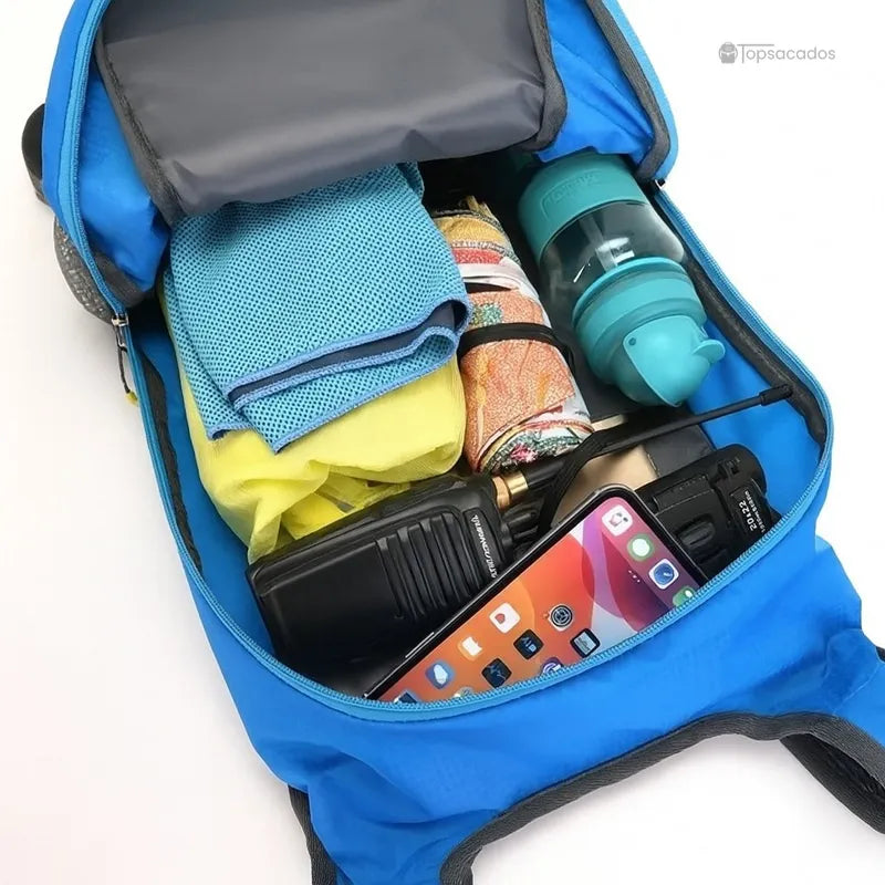 Sac-a-dos-bebe-petite-randonnee ouvert avec contenu visible : vêtements, gourde, talkie-walkie et smartphone.