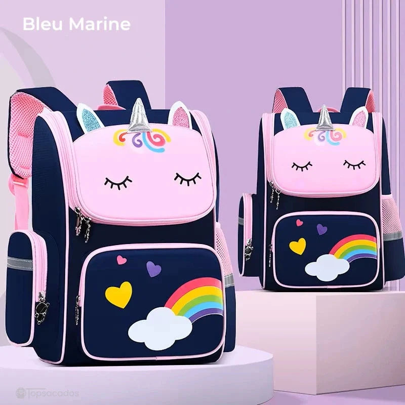 sac a dos petite section bleu marine avec face licorne rose et corne argentée, posé sur socle décoratif, fond violet pastel