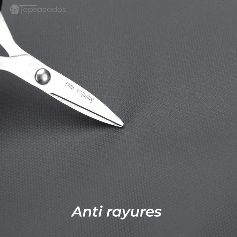 Sac à dos pour étudiant avec tissu anti-rayures testé par des ciseaux, montrant la résistance du matériau extérieur gris foncé.