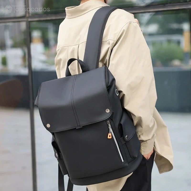 Sac à dos pour étudiant noir porté à l’épaule par un jeune homme vêtu d’une veste beige, dans un environnement citadin.