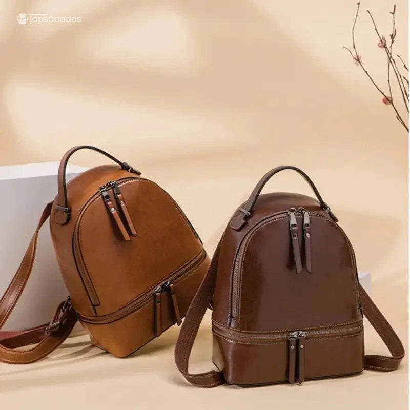Sac à dos pour femme en cuir marron et marron foncé posés côte à côte sur un fond beige avec branches décoratives.