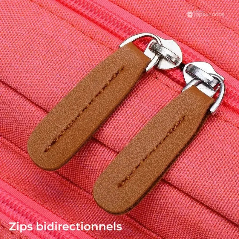 Sac à dos pour lycéen gros plan sur les zips bidirectionnels en cuir synthétique marron sur fond rose.