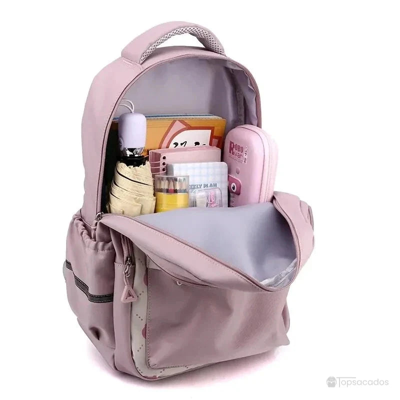 Sac à dos primaire fille ouvert et rempli de fournitures scolaires, organisé en plusieurs compartiments.