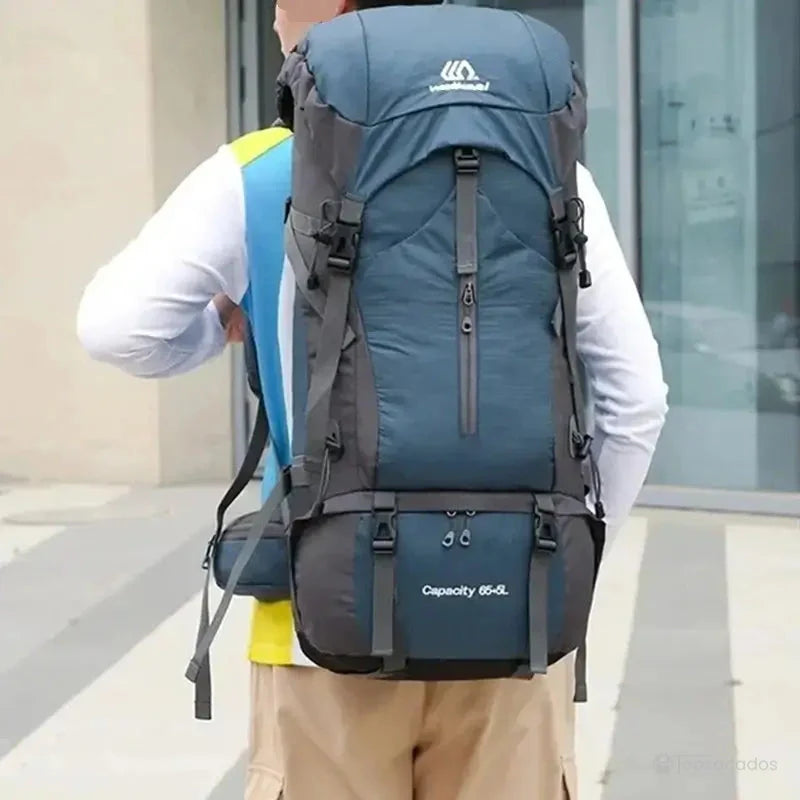 Sac à dos randonnée étanche 65 litres couleur bleu nuit porté en ville par un randonneur, mettant en avant sa capacité et ses attaches solides