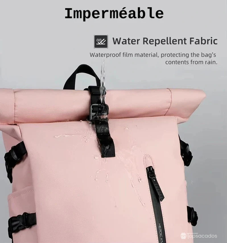 Sac a dos Roll Top pour femme rose en gros plan sous des gouttes d’eau, illustrant la surface imperméable du tissu et la solidité des sangles.