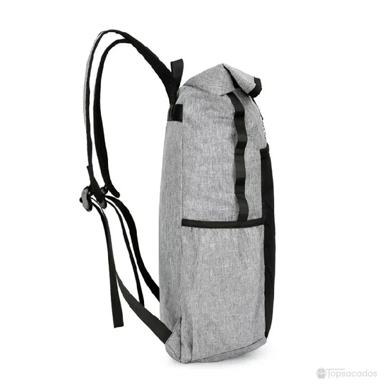 Sac à dos roulé gris vu de profil, avec bretelles réglables et sangle latérale, mis en valeur sur fond blanc.