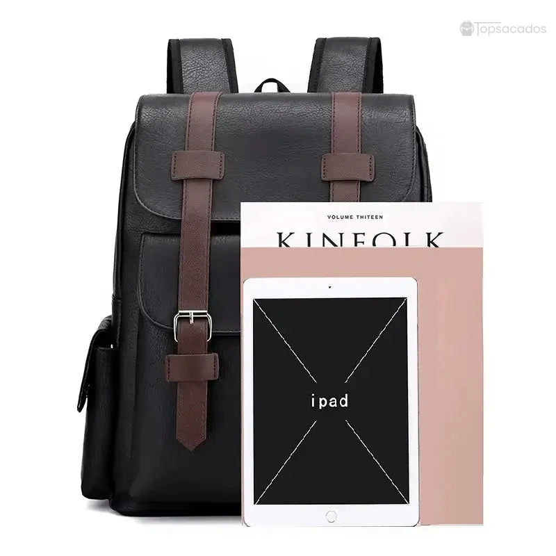 Sac à dos simili cuir noir illustré avec un magazine et une tablette iPad posés devant pour montrer sa capacité.