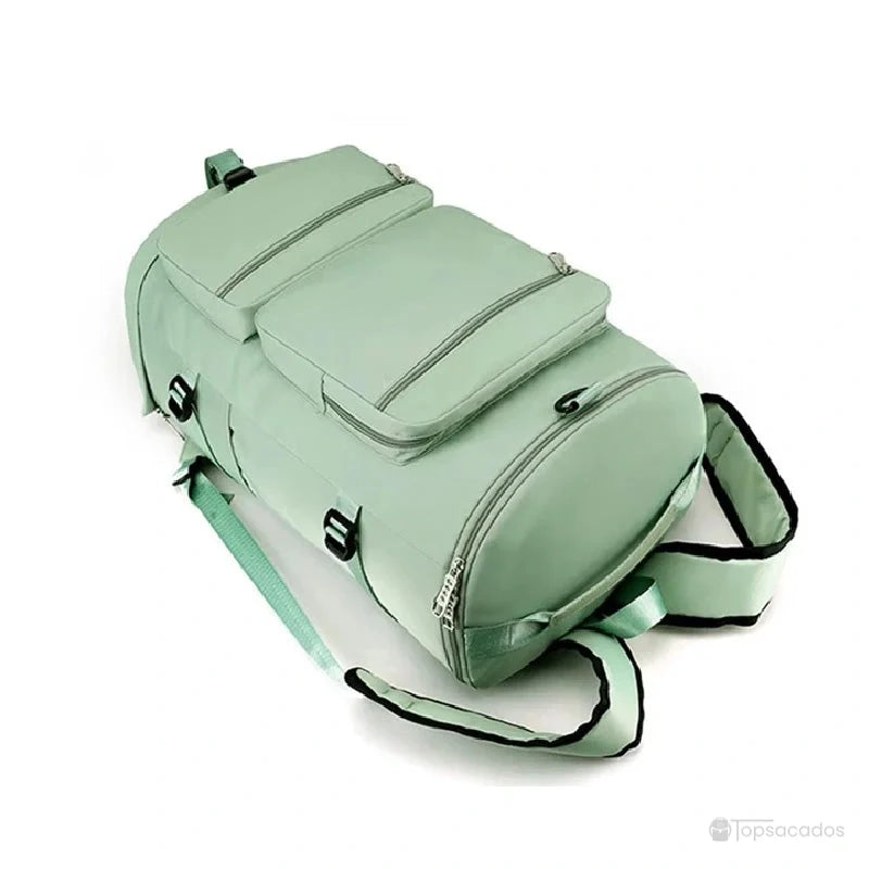 Sac à dos sport grand volume vert clair posé à plat, montrant les bretelles rembourrées et la bandoulière latérale.