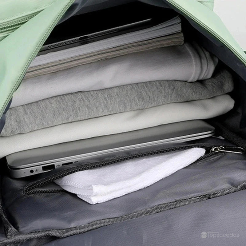 Sac à dos sport grand volume ouvert avec vêtements pliés, ordinateur portable et pochette intérieure zippée contenant une serviette blanche.