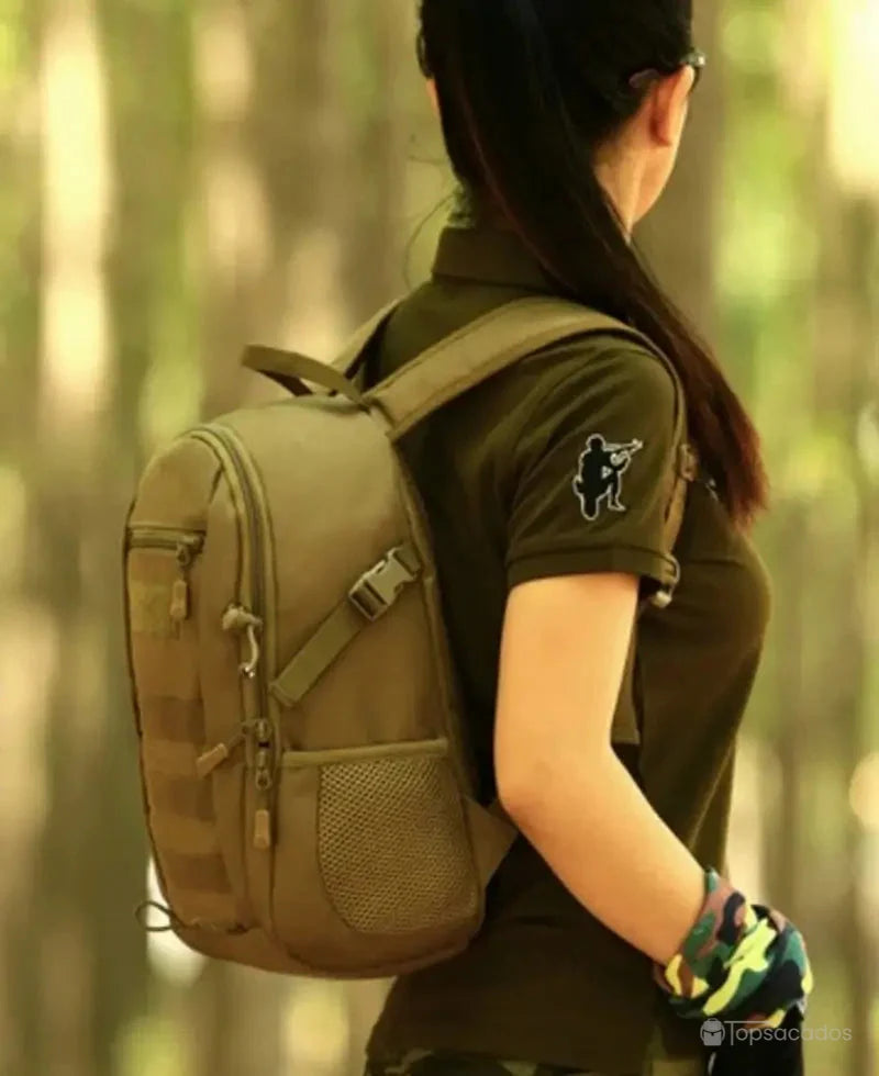 Sac à dos style militaire Femme porté par une femme de profil dans un environnement boisé.